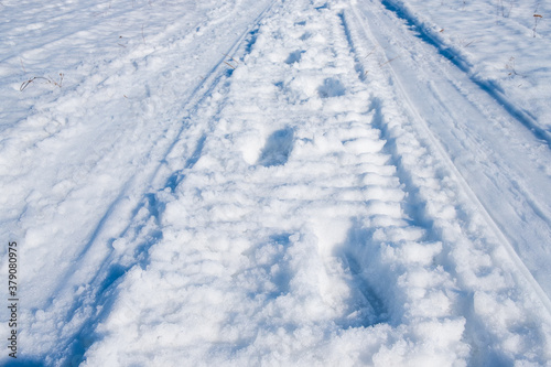 footprints of a person in the snow against the background of snowmobile tracks © metelevan