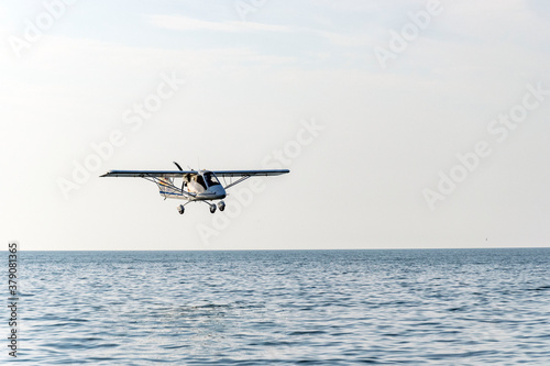 A small plane flies over the sandy seashore.