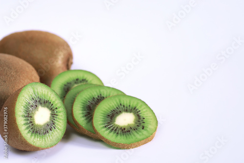 A kiwi fruit is sliced on a white background