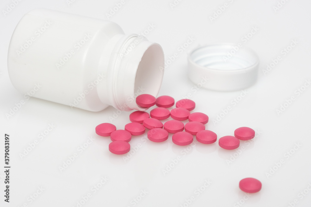 On the white surface is a jar of pills that have spilled out. On the white surface is a jar of pills that have spilled out.