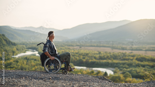 Athlete after serious injury in wheelchair enjoy fresh air in the mountains. Rehabilitation of people with disabilities.