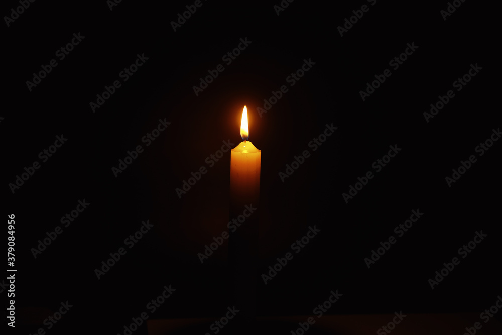 Fototapeta premium Burning candle Wick from a candle in a flame of fire. Symbol of sadness and loneliness. A time of condolences. Burning wax candle. Religion.