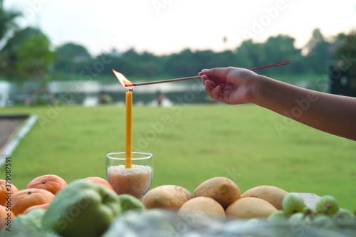 Принти на полотні Hand of people light up the incense with candle during the praying ceremony with blurred landscape background