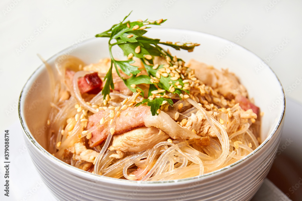 Cellophane noodles with chicken and bacon in a light plate