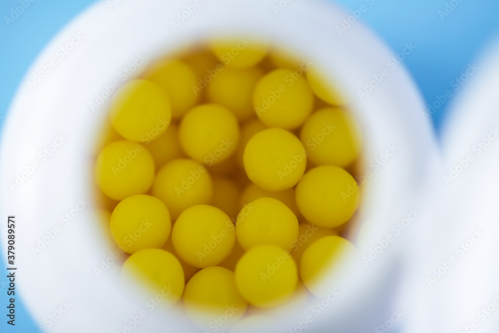 The plastic container of pills on bright blue background. The plastic container of pills on bright blue background.