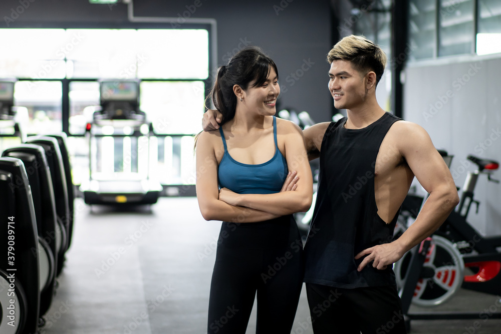Cheerful healthy Asian sportspeople portrait in a gym with copyspace. Asian young sportswoman and sportsman posing for a photography in a indoor gym. 