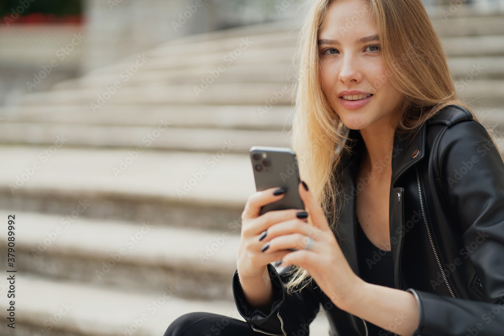 smiling beautiful portrait of a young woman of European appearance. holding the phone in his hands, texting with his best friend about the evening, planning a trip smiling beautiful portrait of a young woman of European appearance. holding the phone in his hands, texting with his best friend about the evening, planning a trip