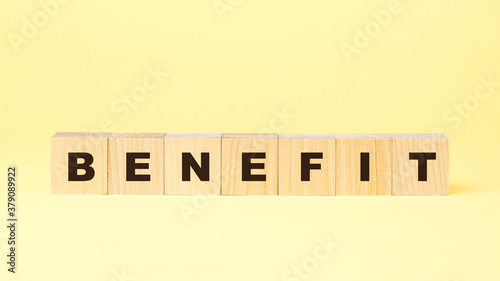word benefit with small wooden blocks on yellow background
