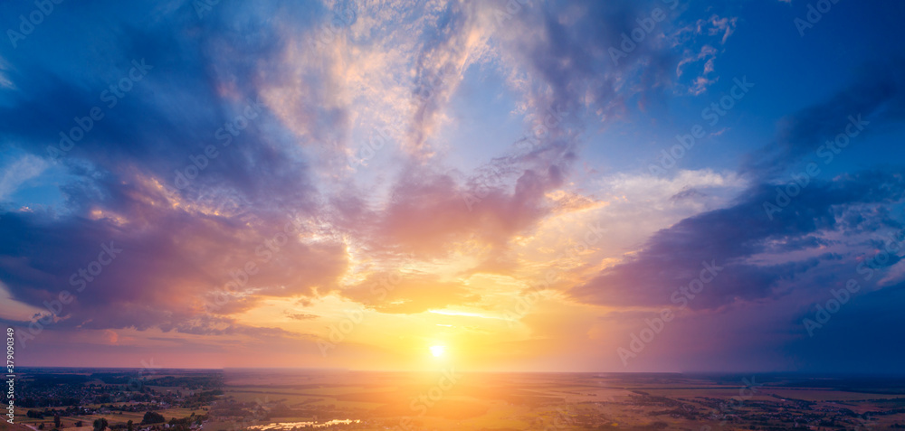 Spring rural landscape in the evening with a beautiful burning sky, aerial view. Panoramic view of pine forest, fields, and river during blazing sunset