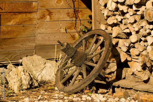 wooden wagon wheel in front of a stack of logs