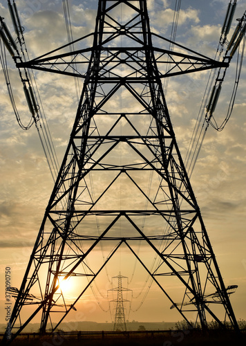 Фотография National grid electricity pylon silhouette at sunrise and framing distant pylons to the horizon