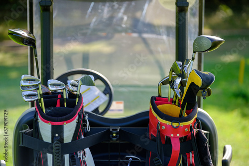 Golf clubs in bags attached to back of golf buggy photo