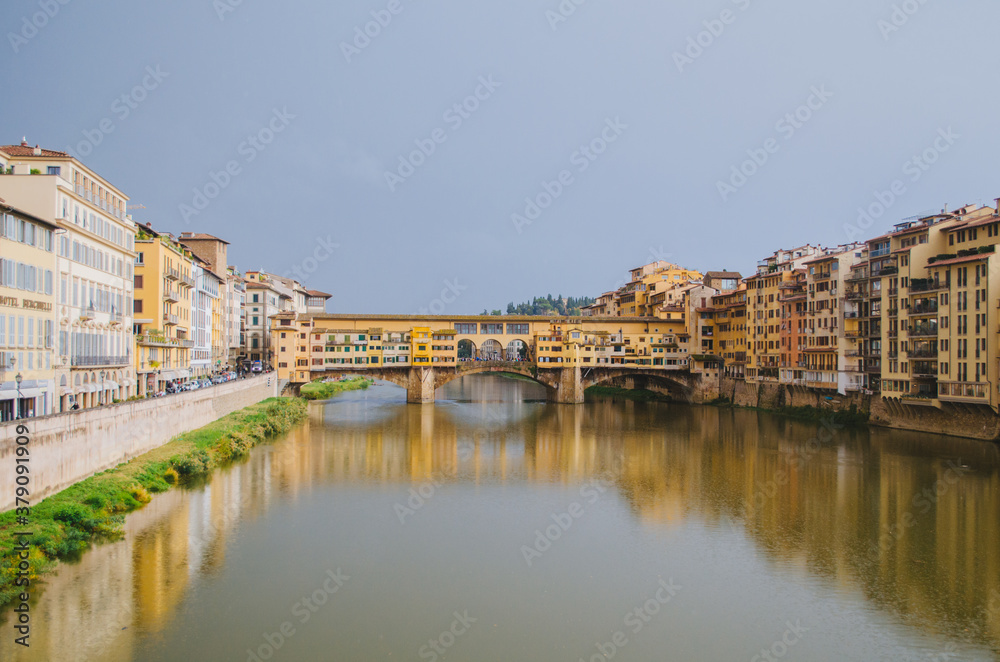 Rome, Italy - A panoramic view of the Ponte Vecchio and the Arno river reflecting the buildings in its water during a cloudy afternoon.