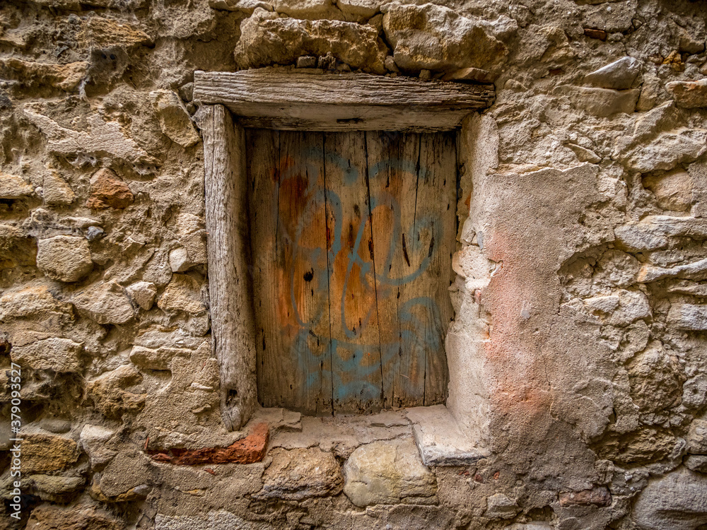 opening in an old stone wall, closed by a colored shutter