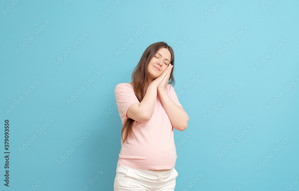 sleepy pregnant woman in pink clothes on a blue background sleepy pregnant woman in pink clothes on a blue background