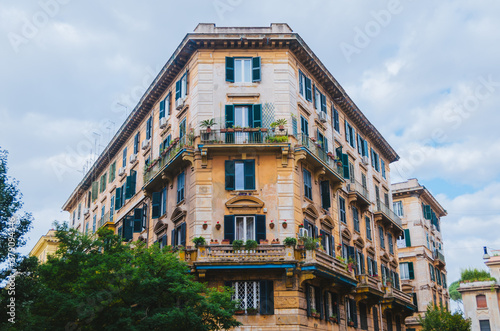 Rome, Italy - A beautifully architectured apartment in downtown Rome during a cloudy afternoon with the classical green windows and outdoor plants positioned below the windows