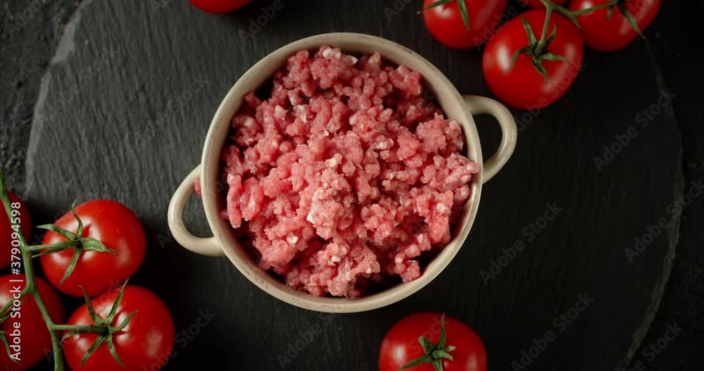Raw minced meat in bowl slowly rotates on a stone board. Raw minced meat in bowl slowly rotates on a stone board.