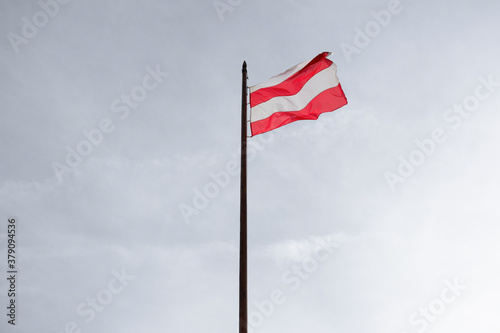 Wavy flag of Brno, Czech Republic / Czechia - flag post and flagpole with heraldic sign and symbol of city and town. Minimalist sky in the background. 