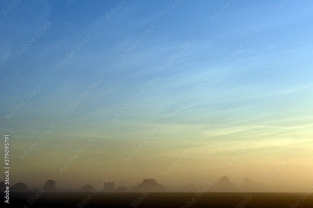 Dawn mist with wispy clouds and light blue sky fading to orange over the village of Bishopstone in Buckinghamshire Dawn mist with wispy clouds and light blue sky fading to orange over the village of Bishopstone in Buckinghamshire