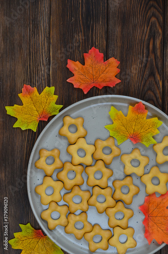 autumn ceramic plate with cookies and maple leaves on a wooden table