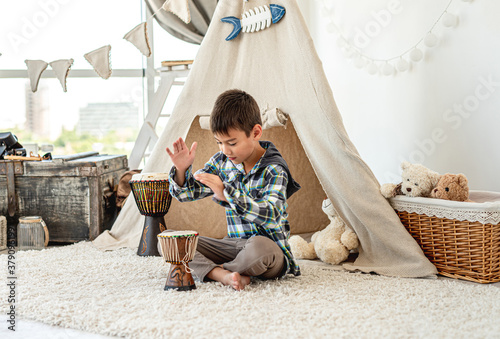 Fotografia Little boy playing djembe drums indoors