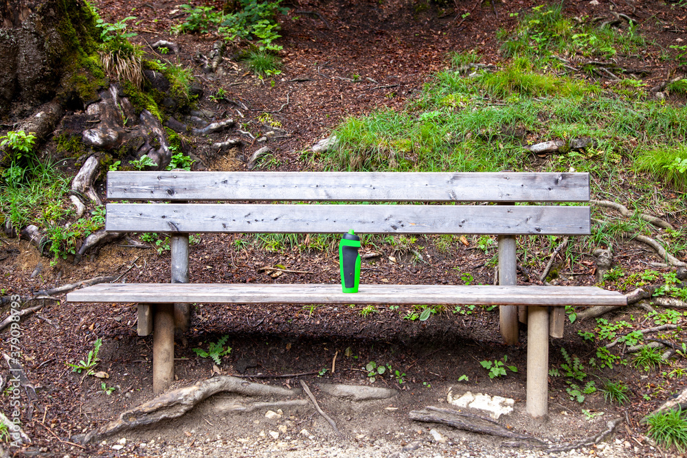 plastic water drinking bottle for sport activity on a wooden bench in public park. take a break plastic water drinking bottle for sport activity on a wooden bench in public park. take a break