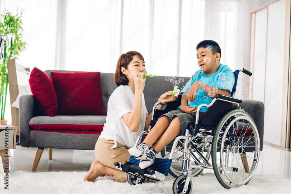 Portrait of enjoy happy love family asian mother playing and carer helping look at disabled son child sitting in wheelchair moments good time at home.disability care concept Portrait of enjoy happy love family asian mother playing and carer helping look at disabled son child sitting in wheelchair moments good time at home.disability care concept