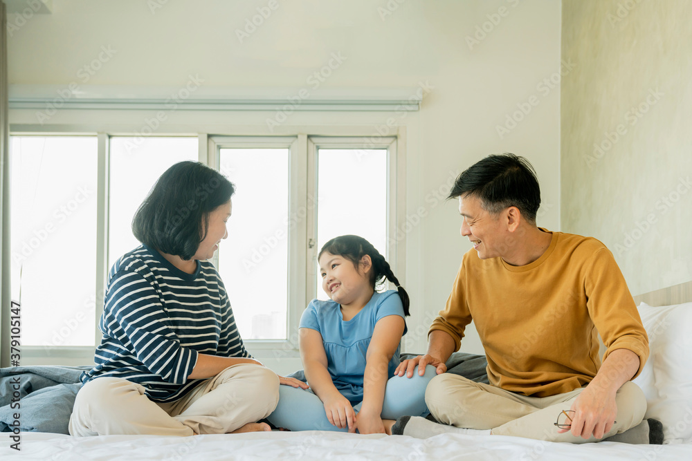 Obraz premium asian Senior grandparents couple laying with grandchildren preety female child on bed in bedroom,happy family play together in the bed