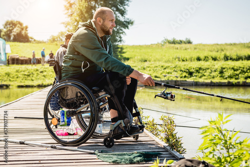 Foto Young disabled man in a wheelchair fishing.