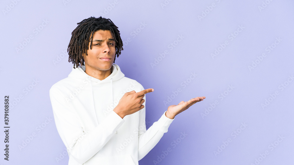 Young african american rasta man excited holding a copy space on palm. Young african american rasta man excited holding a copy space on palm.