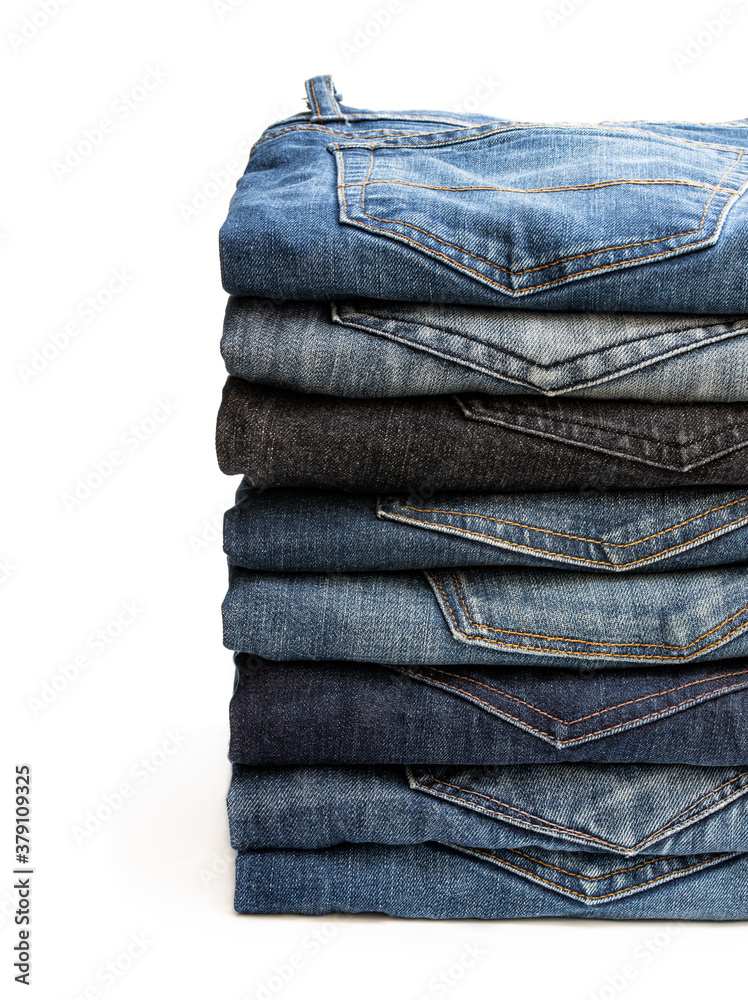Lot of various used unisex jeans stacked in a pile isolated on white Lot of various used unisex jeans stacked in a pile isolated on white