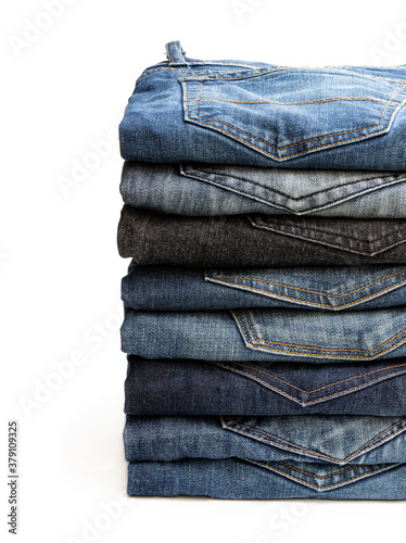 Lot of various used unisex jeans stacked in a pile isolated on white