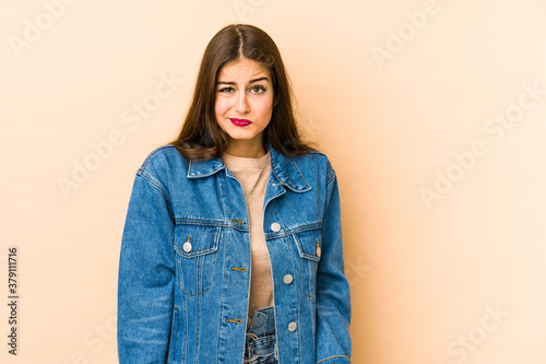 Young caucasian woman isolated en beige background shrugs shoulders and open eyes confused.