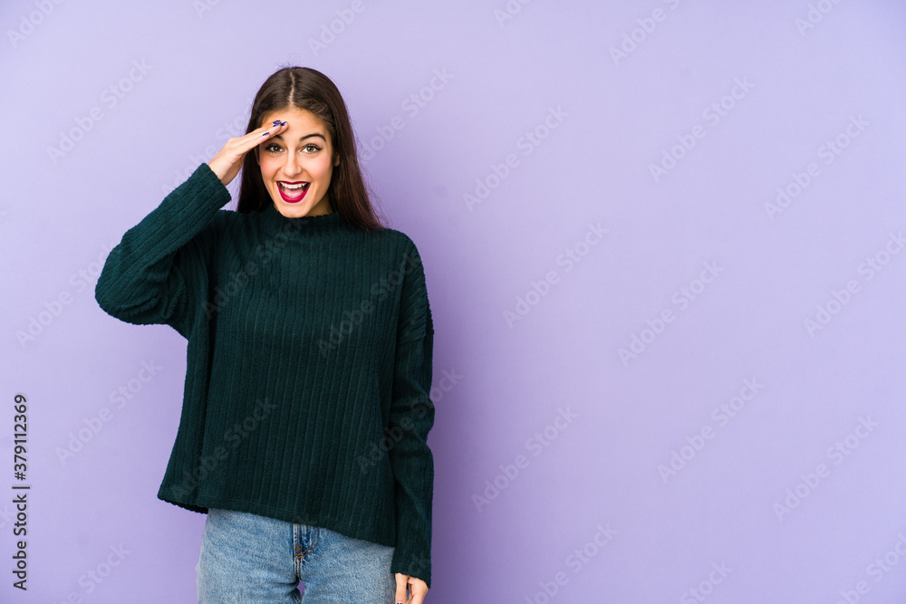 Young caucasian woman isolated on purple background shouts loud, keeps eyes opened and hands tense.