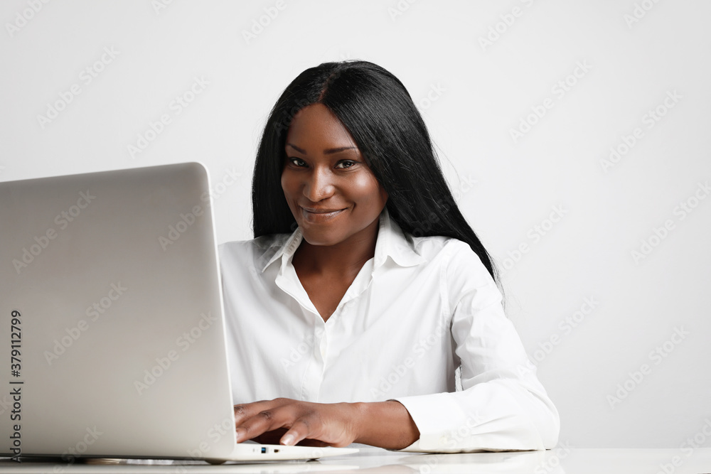 Portrait of confident African American businesswoman smiling at camera at workplace. Posing over white background. Portrait of confident African American businesswoman smiling at camera at workplace. Posing over white background.