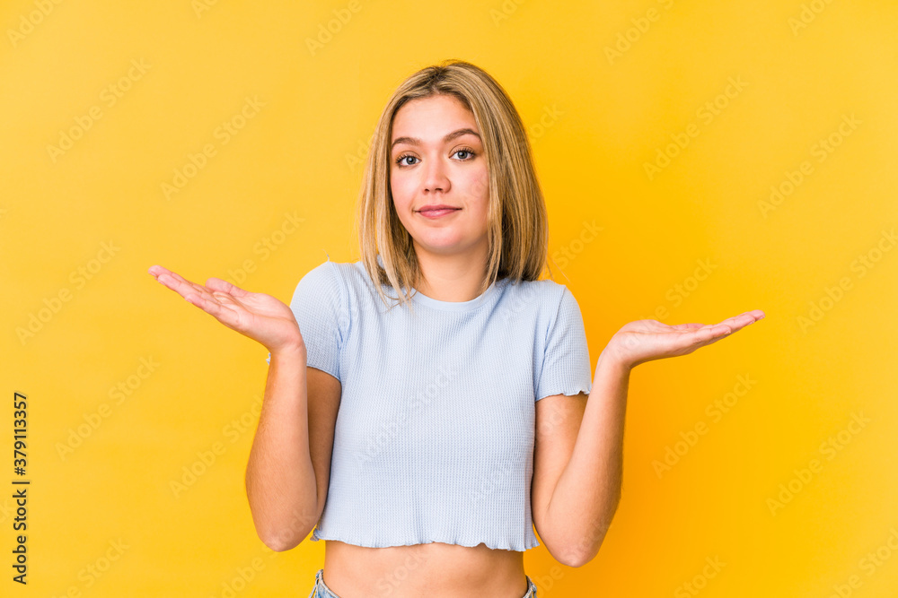 Young blonde caucasian woman isolated doubting and shrugging shoulders in questioning gesture.