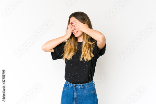 Young caucasian woman isolated on white background afraid covering eyes with hands.