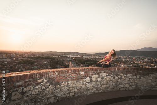 Woman practicing yoga or pilates at sunset or sunrise in beautiful city location.