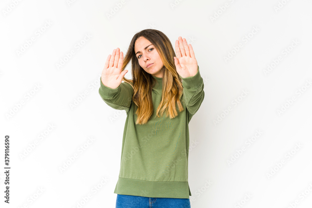 Young caucasian woman isolated on white background standing with outstretched hand showing stop sign, preventing you.