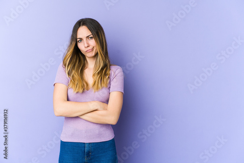 Young caucasian woman isolated on purple background frowning face in displeasure, keeps arms folded.