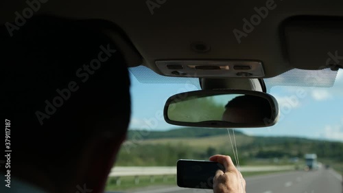 Wallpaper Mural A young guy takes pictures of a mountain landscape through the windshield of a car driving on a freeway. Tourists travel the world. Torontodigital.ca