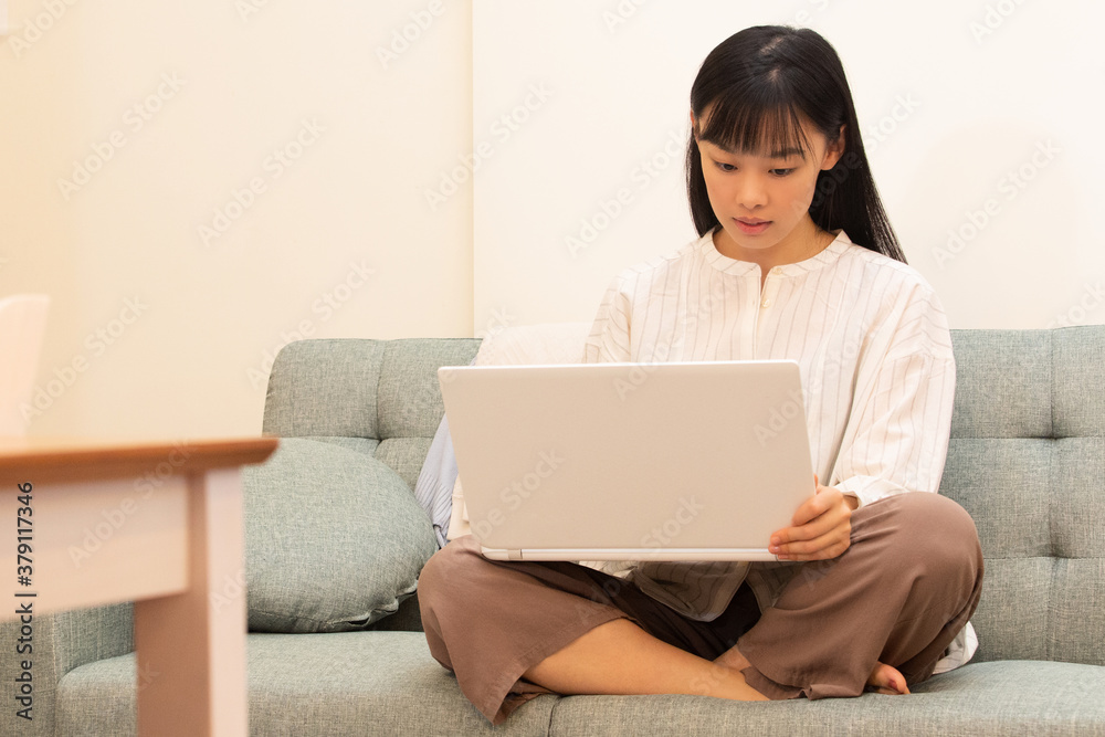 リモートワーク 自宅のソファで仕事をする若く美しい女性 リモートワーク 自宅のソファで仕事をする若く美しい女性