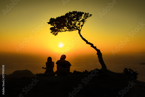 Romantic couple in peaceful scenery on Rhodes beach under the tree in sunset shine