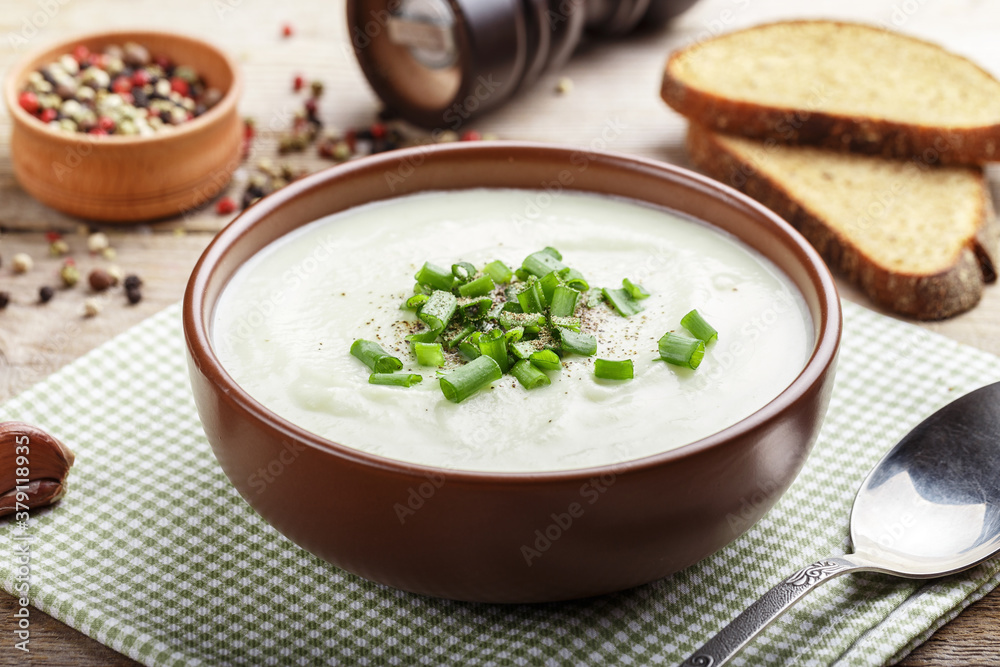 cauliflower cream soup on a table in a clay plate. nearby are spices.