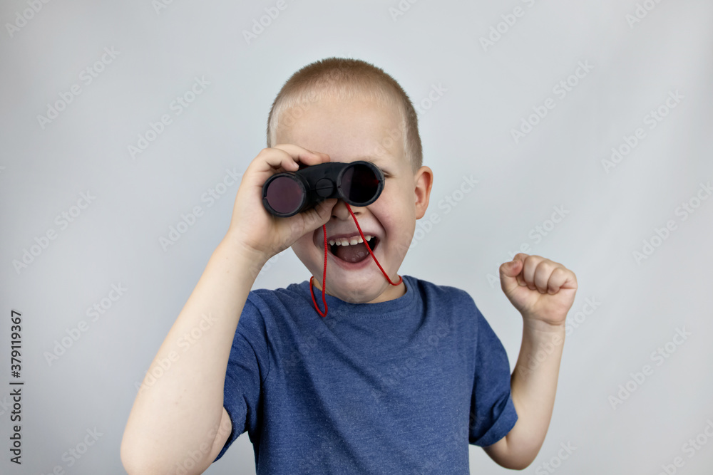 A boy with binoculars looks into the distance and smiles. Facial expression and body position show victory. The concept of vision for success, business confidence and overcoming difficulties. A boy with binoculars looks into the distance and smiles. Facial expression and body position show victory. The concept of vision for success, business confidence and overcoming difficulties.