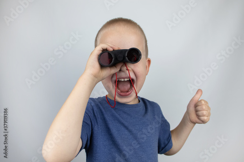 A boy with binoculars looks into the distance and smiles. Facial expression and body position show victory. The concept of vision for success, business confidence and overcoming difficulties.