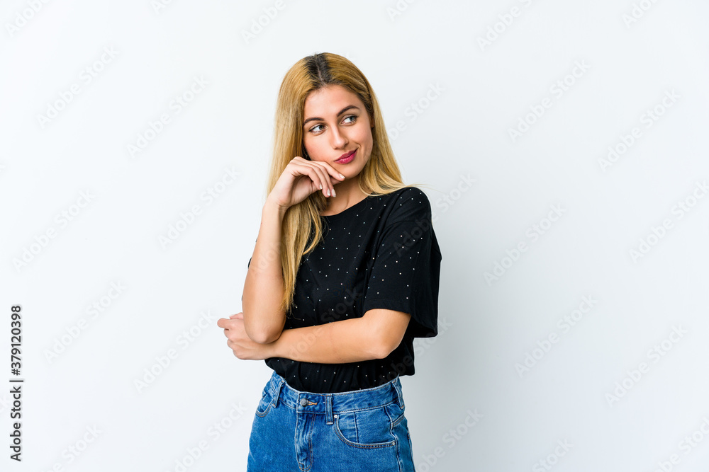 Young blonde woman isolated on white background looking sideways with doubtful and skeptical expression.