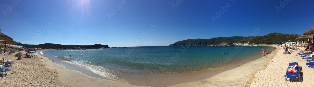 Sunny beach panorama in Greece on sunny day with mountain on background clear blue sky