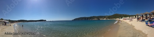 Sunny beach panorama in Greece on sunny day with mountain on background clear blue sky
