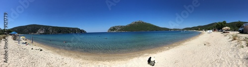 Fototapeta Naklejka Na Ścianę i Meble -  Sunny beach panorama in Greece on sunny day with mountain on background clear blue sky